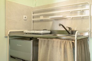 A compact kitchenette with a built-in refrigerator, a sink, and a microwave.