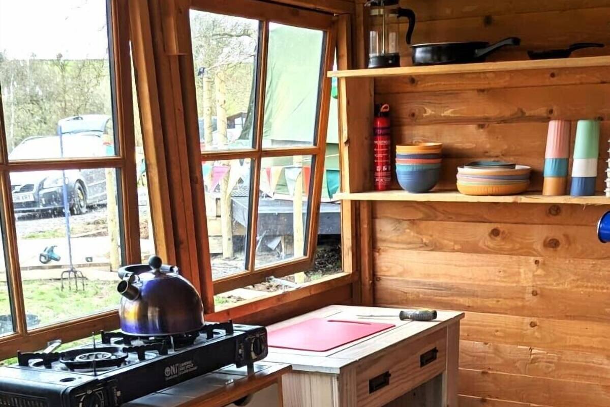 Een keuken met een gasfornuis, houten planken en een geruite vloer.