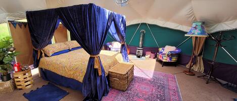 Un dormitorio acogedor con cama con dosel, un pequeño calentador, una lámpara y vistas al exterior.
