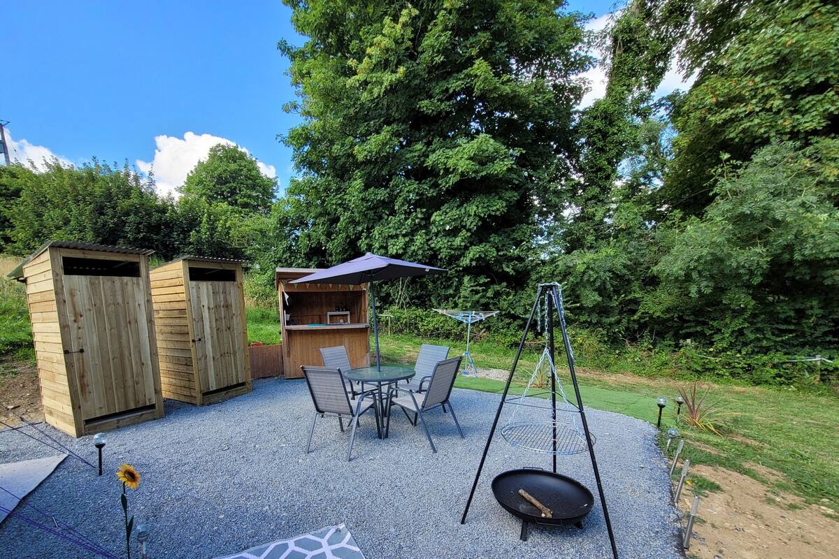 Een terras met een tafel, stoelen, een schommel en houten constructies.