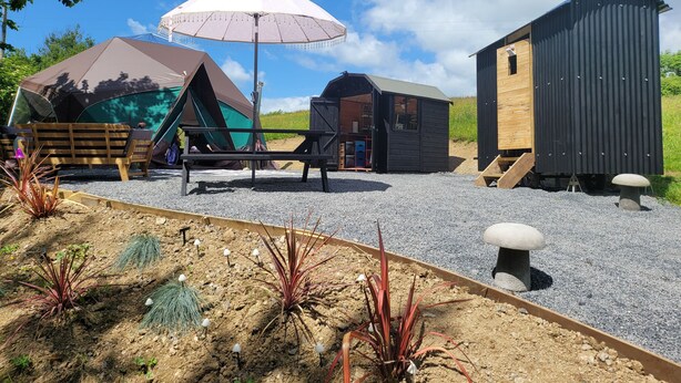A campsite with tents, a wooden bench, and a small shed. - Hideaway Escapes (Narberth)