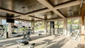 Una palestra con diverse attrezzature per esercizi, ampie finestre e vista sull'esterno.