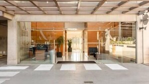 Ingresso moderno di un edificio con porte in vetro, una reception ben visibile e un percorso chiaro verso l'interno.