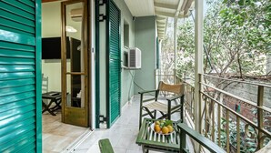 Un balcone con un tavolo, una sedia e una ciotola di frutta.