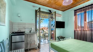 Ein Zimmer mit Bett, Küchenzeile und einem Balkon mit Aussicht.