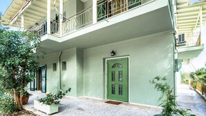 Ein zweistöckiges Gebäude mit grüner Tür, einem Balkon mit Geländer und einer kleinen Veranda.