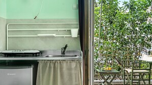 Eine kompakte Küche mit Kühlschrank, Spüle und einem kleinen Tisch mit einer Obstschale.