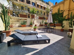 An outdoor patio area with two lounge chairs, a table, and several potted plants. - BnB Rooms And Comfort (Rome)