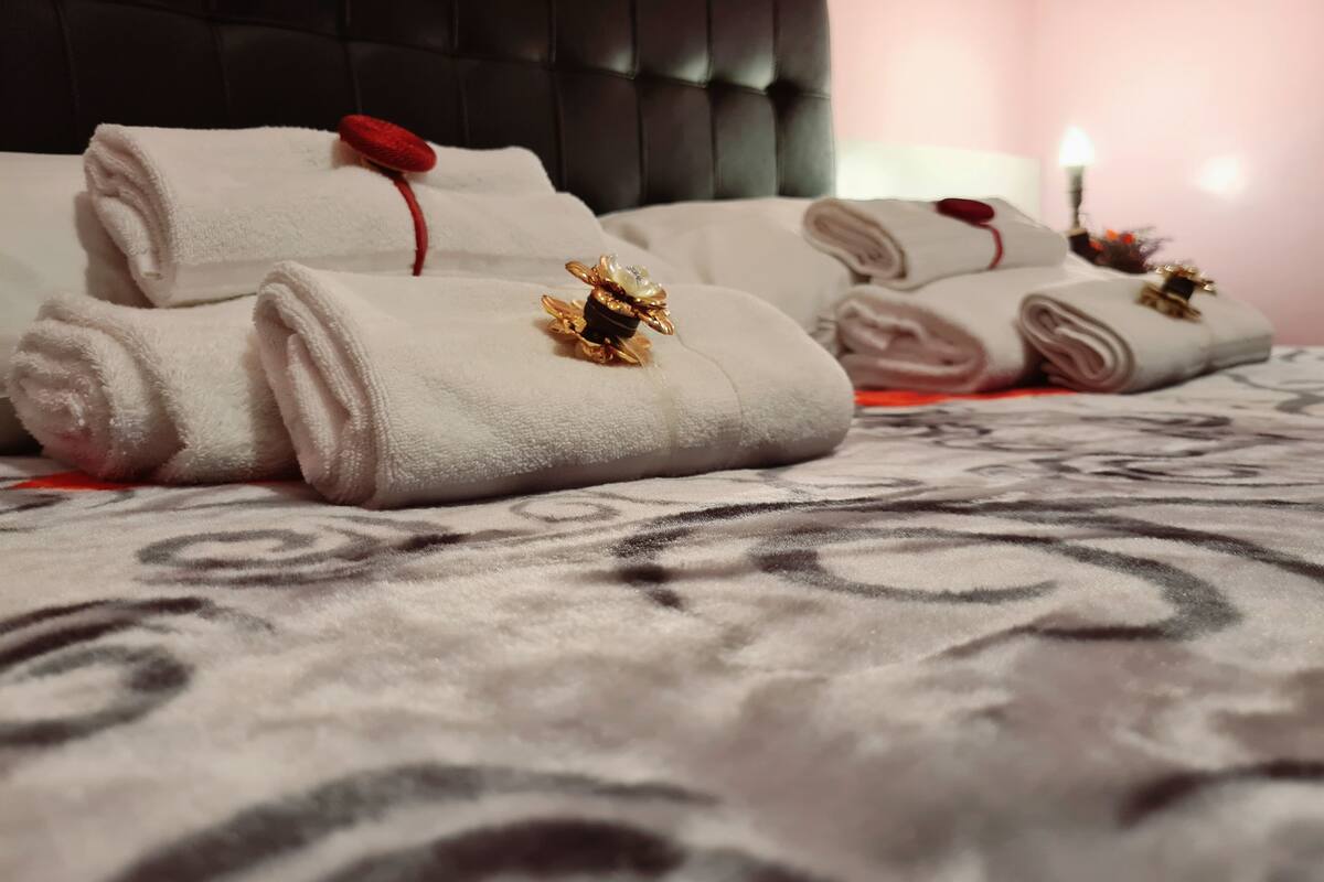 Toallas dobladas cuidadosamente con flores decorativas sobre una colcha estampada en una habitación de hotel.