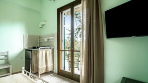 Une chambre avec un lit, un bureau, une fenêtre avec des rideaux, une télévision et un radiateur.