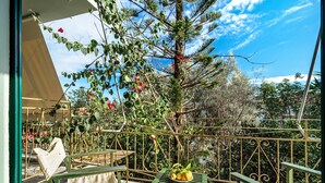 Un balcon avec une table verte, un banc et une rambarde.