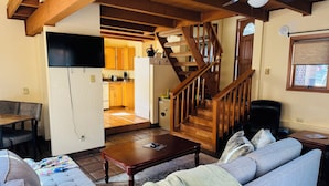 A living room with a wooden staircase, a sofa, a coffee table, and a television.