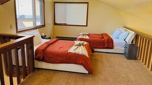 A bedroom with two beds, wooden headboard, a small nightstand, and a ceiling fan.