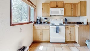 A kitchen with wooden cabinets, a white stove, and a microwave.