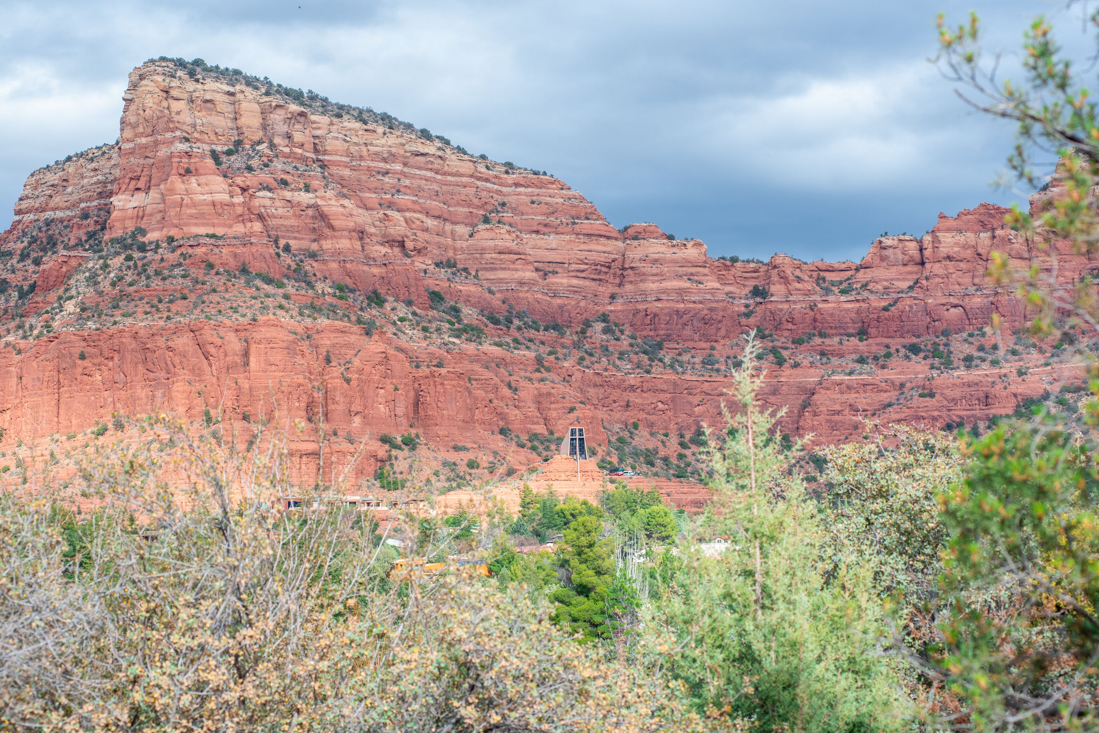A red rock formation with a small building in the foreground.