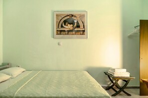A bedroom with a bed, a framed artwork on the wall, and a small table with towels.