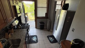 A kitchen with a stove, sink, refrigerator, and a dining area with a table and chairs. - Hyde Park/ Bronzeville Apartment 3E (Chicago)