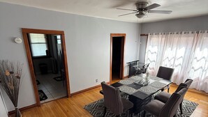 A dining area with a table and chairs, a ceiling fan, and a view through a doorway. - Hyde Park/ Bronzeville Apartment 3E (Chicago)
