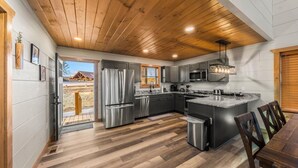 Une cuisine moderne avec un plafond en bois, des appareils en acier inoxydable et un grand îlot central.
