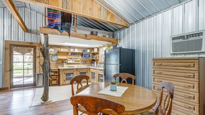 A rustic kitchen with wooden cabinets, a dining table, and a large window.