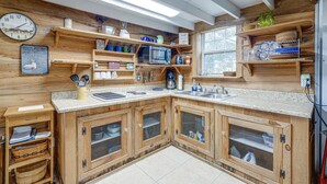 A kitchen with wooden cabinets, a microwave, and various kitchen utensils.