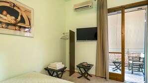 A hotel room with a bed, a TV, a small table with a basket, and a balcony with outdoor furniture. - Studio Apartment 'Old Boat Double Studio 2' with Sea View, Wi-Fi and Air Conditioning (Lefkada)