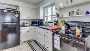 Une cuisine moderne avec des meubles blancs, un réfrigérateur noir, un four à micro-ondes, une cuisinière et un évier.
