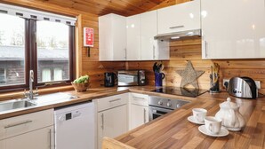 A modern kitchen with wooden cabinets, a stainless steel sink, and a coffee station. - Latrigg Lodge (Keswick)