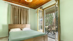 A bedroom with a wooden bed, a view of the outdoors through a glass door, and a ceiling with wooden beams. - Apartment 'Old Boat' with Sea View, Wi-Fi and Air Conditioning (Lefkada)
