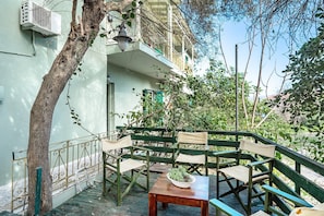 An outdoor seating area with a wooden table and chairs, a railing, and a tree. - Apartment 'Old Boat' with Sea View, Wi-Fi and Air Conditioning (Lefkada)