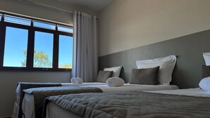 A hotel room with two beds, a large window with curtains, and a view of trees outside. - Recanto Amana Casa Centro de SJBVista (Sao Joao da Boa Vista)