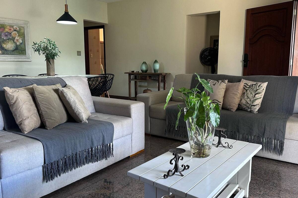 A living room with two grey sofas, a white coffee table, and a potted plant.