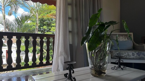 A room with a table, a potted plant, a sofa, and a balcony with a railing. - Recanto Amana Casa Centro de SJBVista (Sao Joao da Boa Vista)