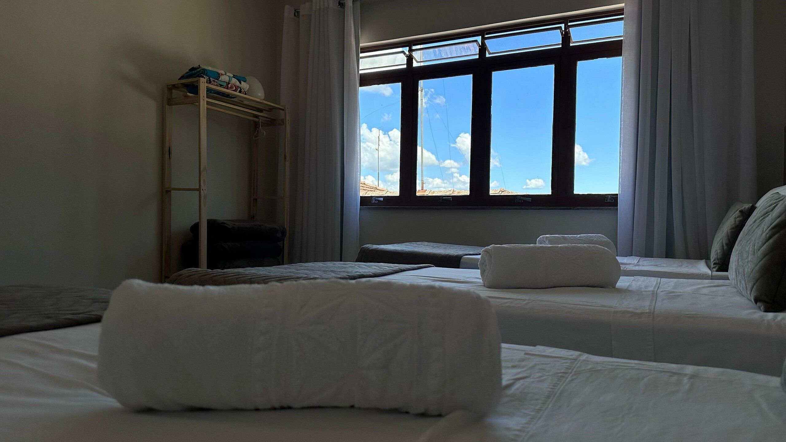 Une chambre avec deux lits, une fenêtre donnant sur le ciel et une étagère sur laquelle sont posés divers objets.