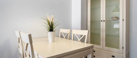A dining table with chairs, a potted plant, and a cabinet with glass doors.