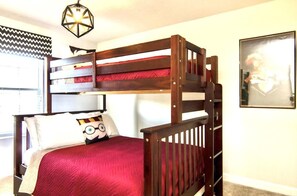 A bunk bed with a red mattress, a white pillow with a cartoon character, and a wooden headboard.