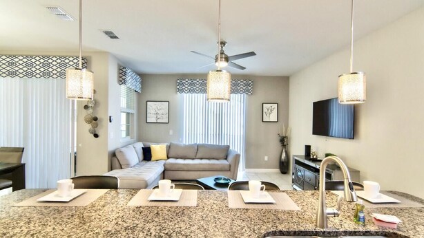 A modern kitchen with granite countertops, a built-in sink, and pendant lighting. - Family Townhome near Disney! Patio w/Pvt Splash Pool, Modern Decor,Free wifi, Resort w/waterpark! (Kissimmee)