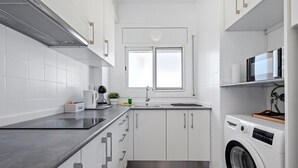 Una cocina moderna con armarios blancos, lavadora integrada y una ventana sobre el fregadero.