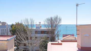 A coastal residential area with buildings, a clear sky, and the sea in the background.