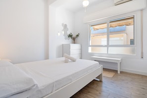 A modern bedroom with a bed, a desk, and a window with blinds.