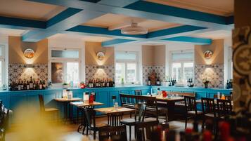 Enjoy dining in a beautifully designed restaurant with patterned tile walls, wine bottles on display, and comfortable seating for guests.
