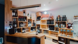 Une boutique de vente de boissons alcoolisées avec des étagères en bois remplies de bouteilles et de verres de toutes sortes.