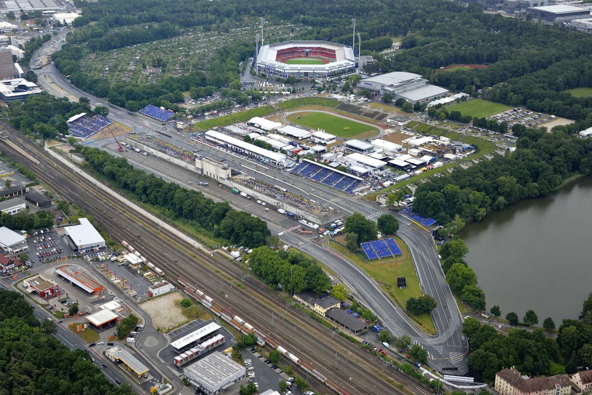 An aerial view of a stadium surrounded by roads, parking areas, and a body of water.