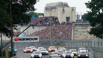 Une compétition automobile où plusieurs voitures s’affrontent sur une piste, entourées de spectateurs.