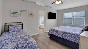A bedroom with two beds, a ceiling fan, a TV, and artwork on the wall. - Homey 3/2, near Fleming Island (Middleburg)