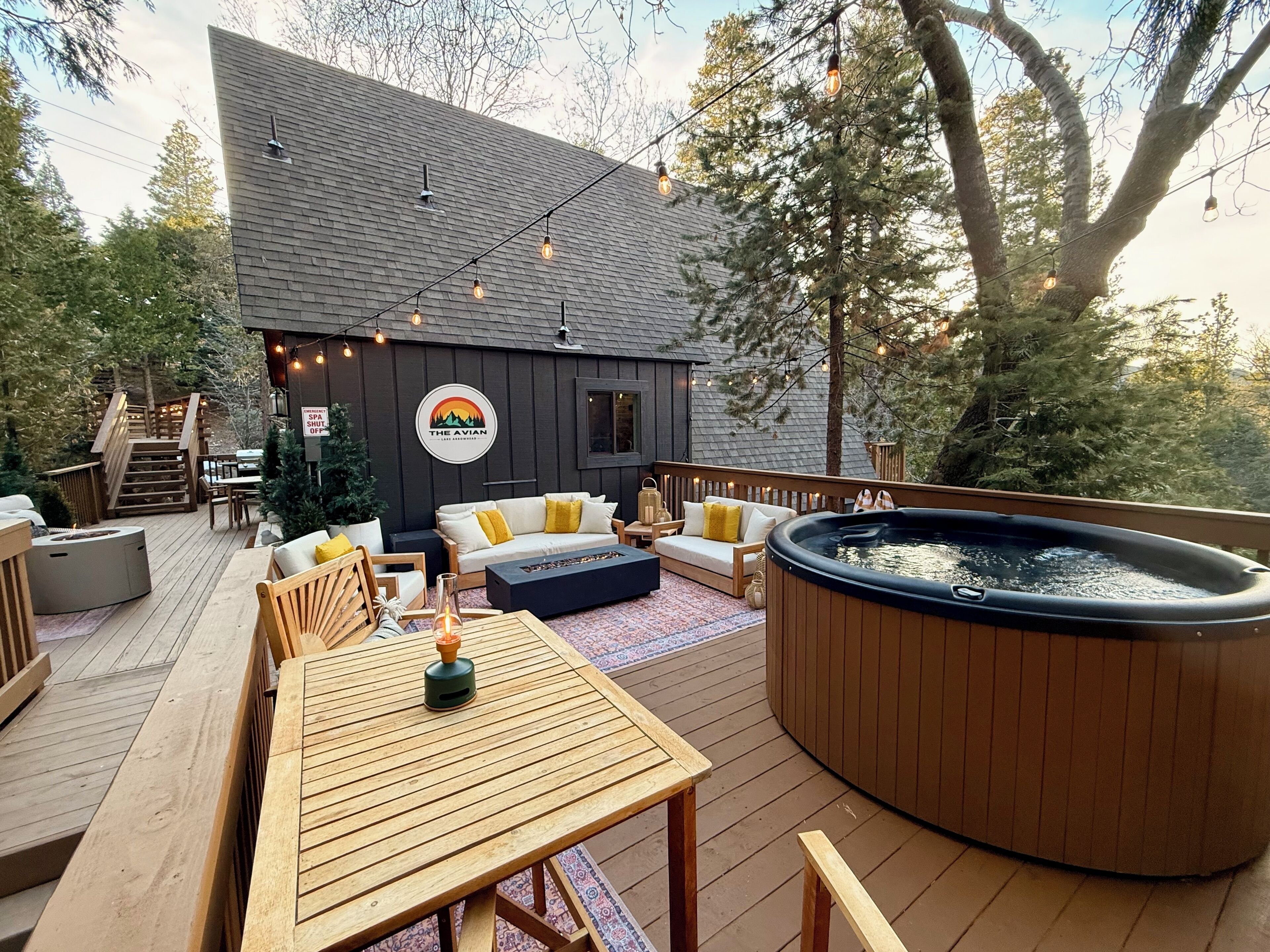 A wooden deck with outdoor seating, a hot tub, and string lights.