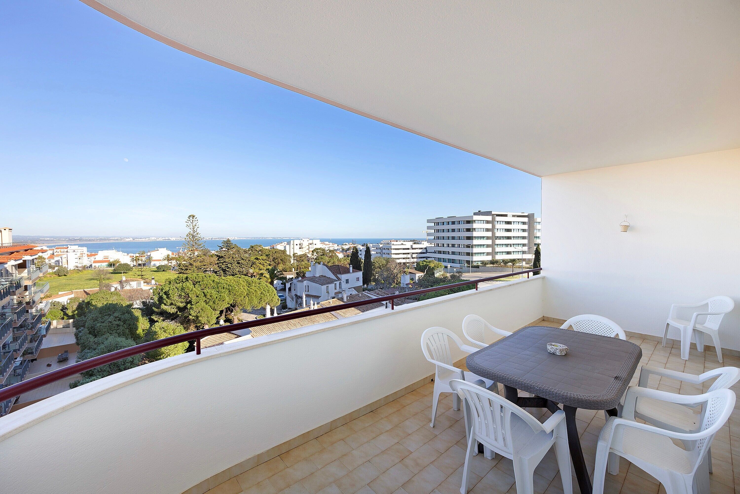 A balcony with a table and chairs, a view of the city, and a railing.