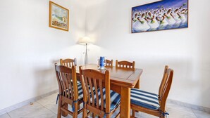 Un comedor con una mesa y sillas de madera, una lámpara y dos cuadros en la pared.
