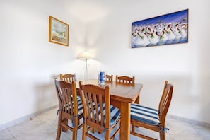 Un coin repas avec une table et des chaises en bois, une lampe et deux œuvres d’art encadrées accrochées au mur.