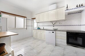 A kitchen with white cabinets, a dishwasher, a stove, and a window.